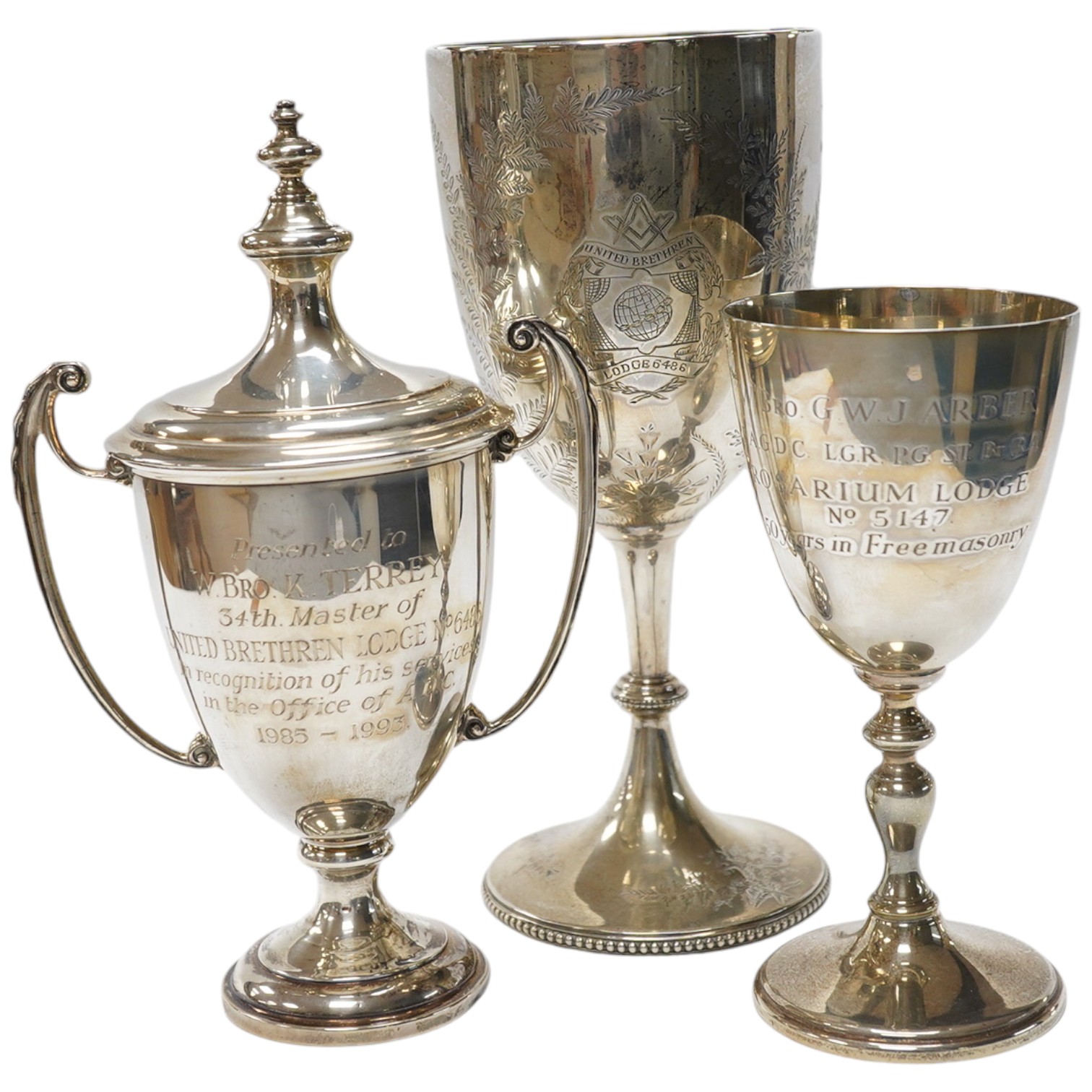 A Victorian engraved silver presentation goblet, with Masonic inscription, London, 1880, 19.5cm, together with a modern silver presentation goblet and a silver two handled presentation trophy cup and cover, 20.2oz. Condi